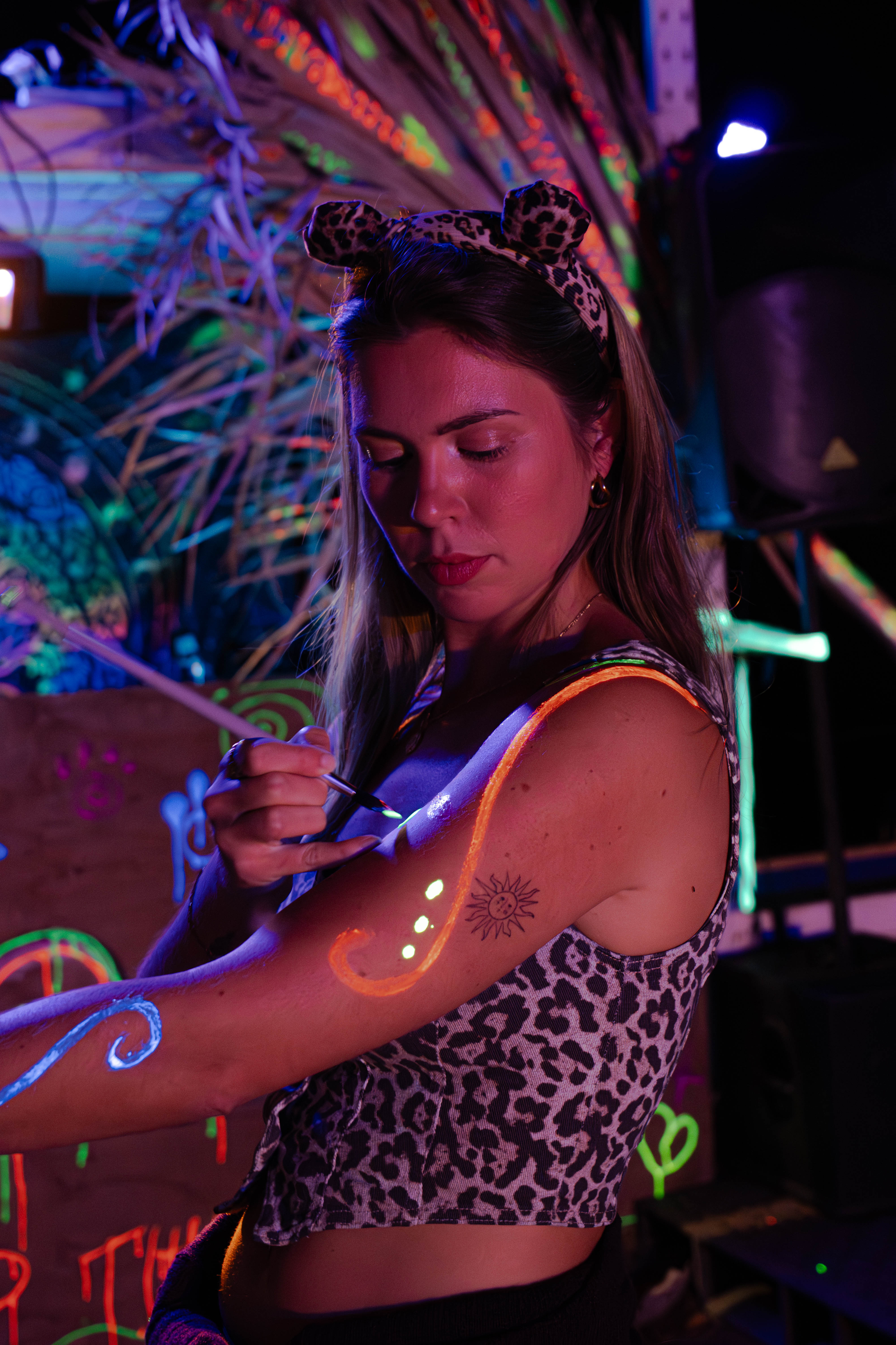 A woman painting a fluorescent pattern on her arm at night