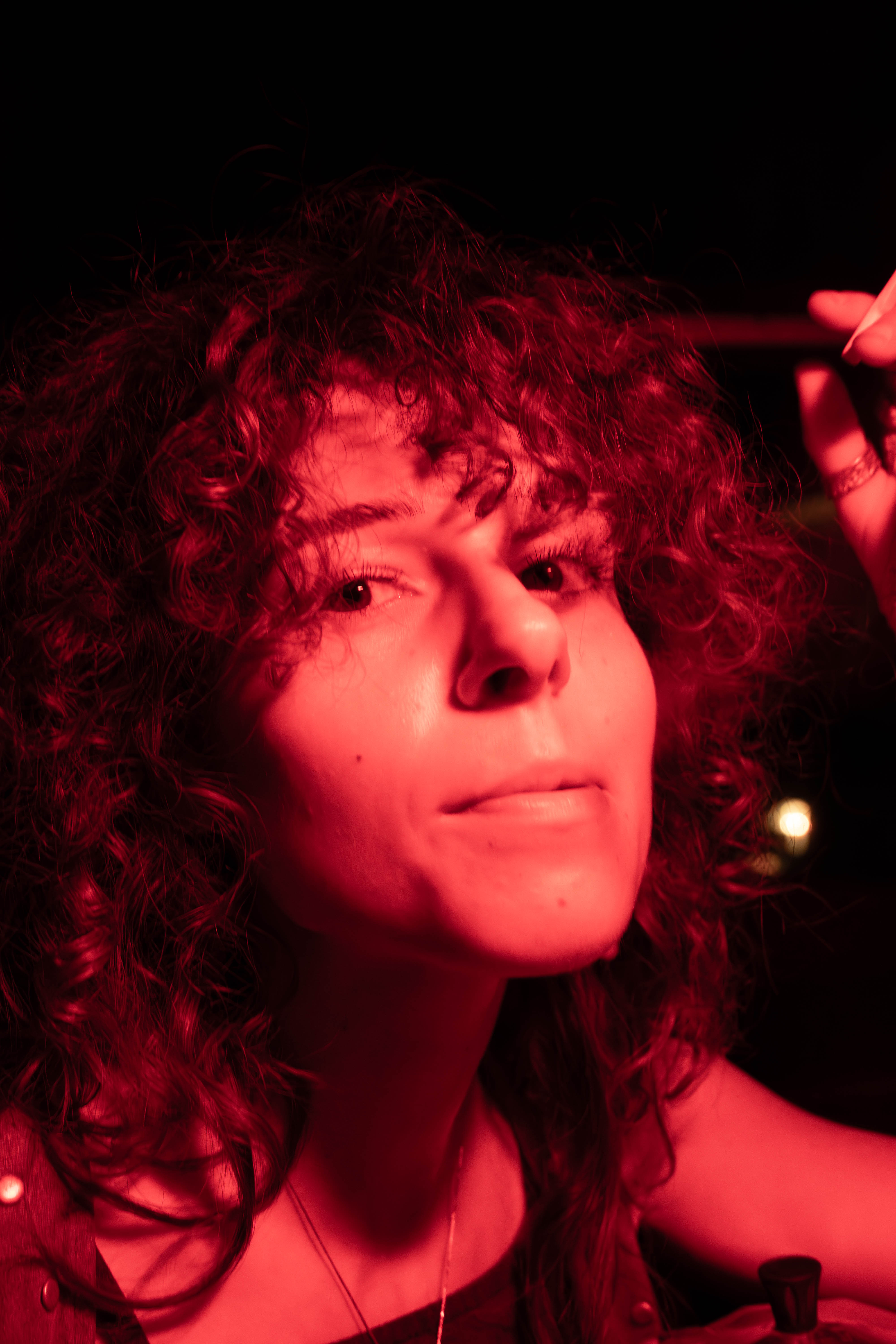 Close portrait of a curly-haired woman illuminated by deep red light