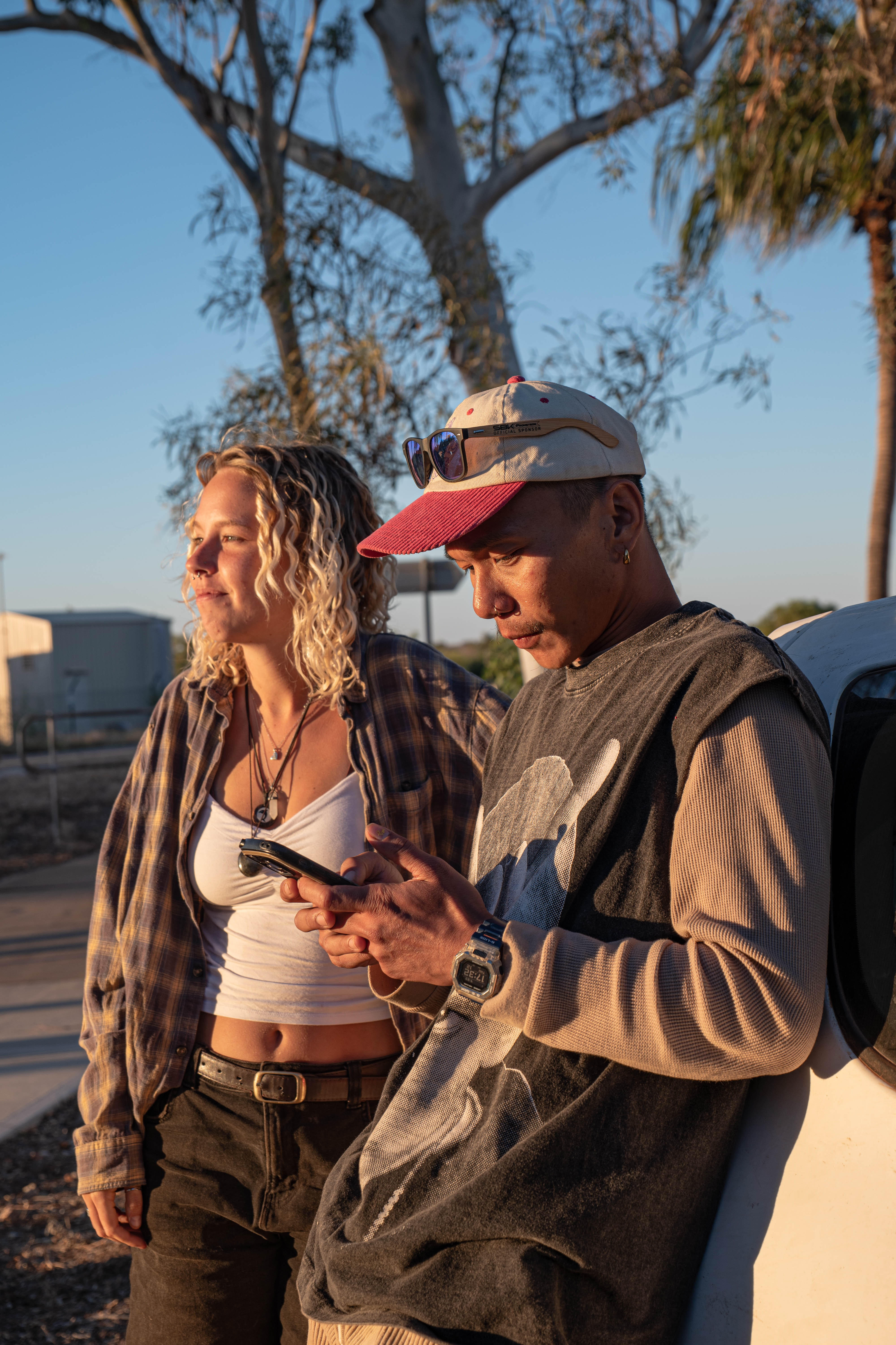 Two friends leaning against a vehicle in warm late-afternoon sunlight